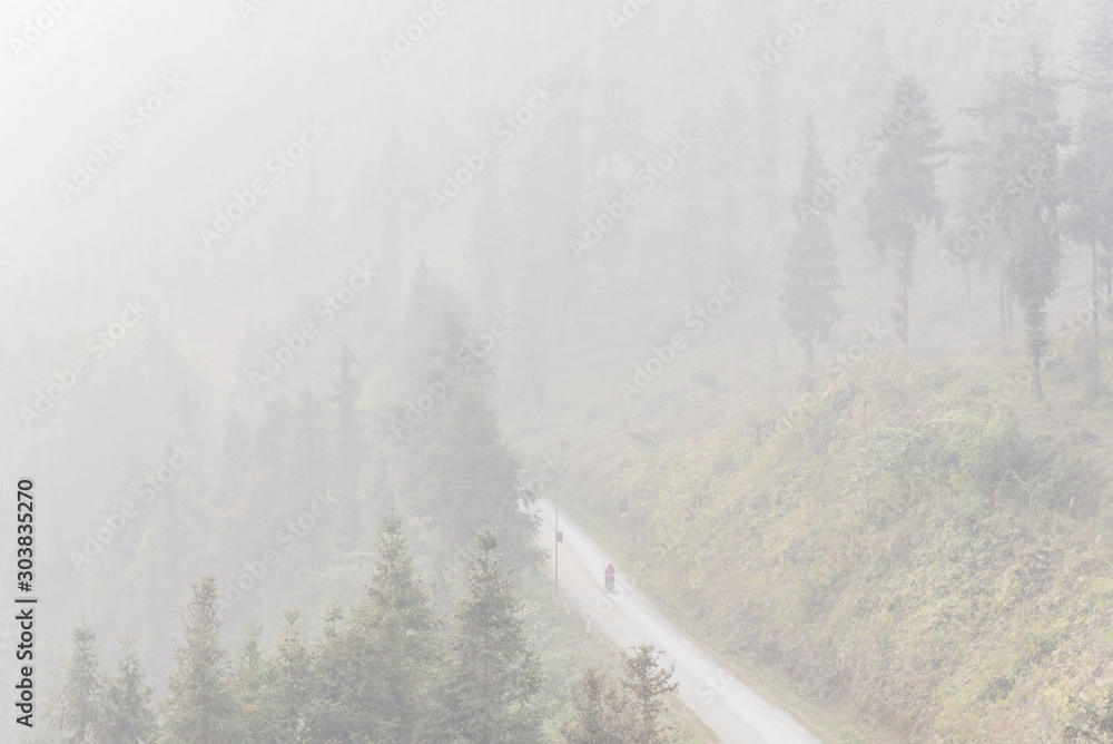 Lonely Asian lady riding a motorbike thru the foggy mountain road in the North Vietnam Lonely Asian lady riding a motorbike thru the foggy mountain road in the North Vietnam