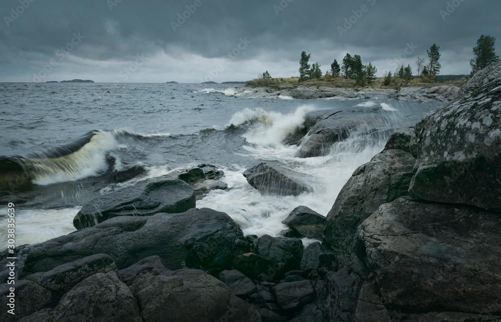 Waves of stormy sea break on rocky shore. Horizontal layout