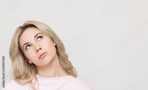 funny beautiful blonde girl grimaces at the camera, she playfully behaves, pink background