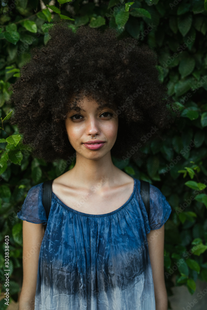 Φωτογραφία Portrait of a young woman with afro hair - Millennial with a green wall of leave