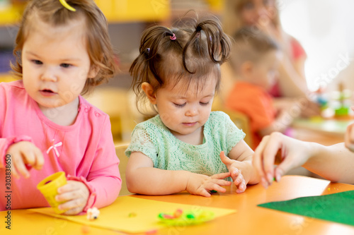 Little kids having fun together with colorful modeling clay at daycare. Children playing with plasticine or dough.