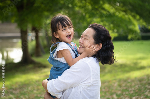Adorable asian granddaughter is playing and laughing together with grandmother with fully happiness moment in the green park, concept of love and relation of difference generation in family lifestyle