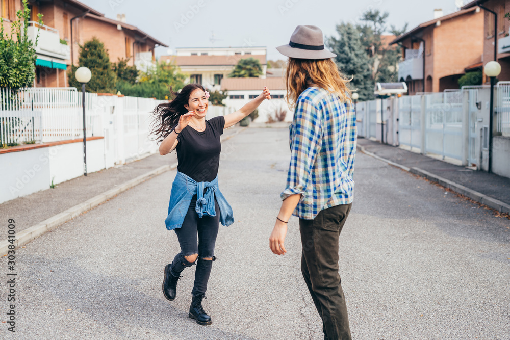Young beautiful bearded man dancing with smiling girlfriend outdoor