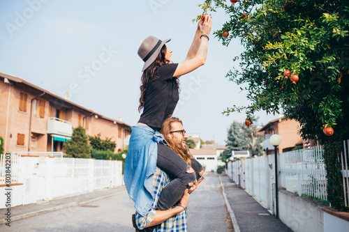 Young woman shoulder riding her bearded boyfriend outdoor picking pomegranate photo