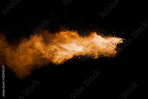 Orange color powder explosion on black background.