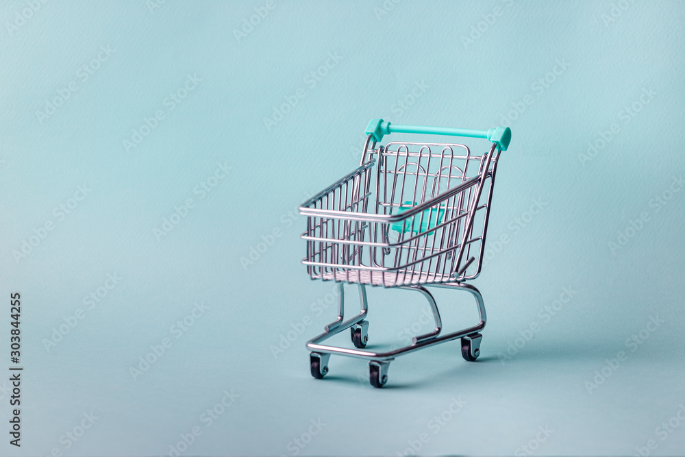 Small empty shopping cart on bright blue background with copy space Small empty shopping cart on bright blue background with copy space