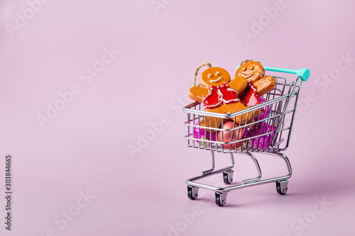 shopping cart full of christmas presents on bright pink background