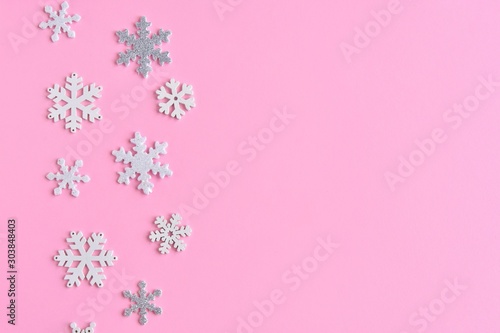 Pink Christmas background with white and silver snowflakes border and empty space for  text, selective focus. New year flat lay with snowflakes decorative border. Winter postcard.  © Tetiana Ivanova