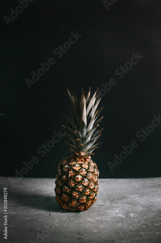 Dark photo of a pineapple on a stone surface