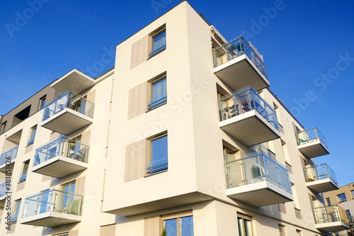 Exterior of a modern white apartment building with balcony. No people.