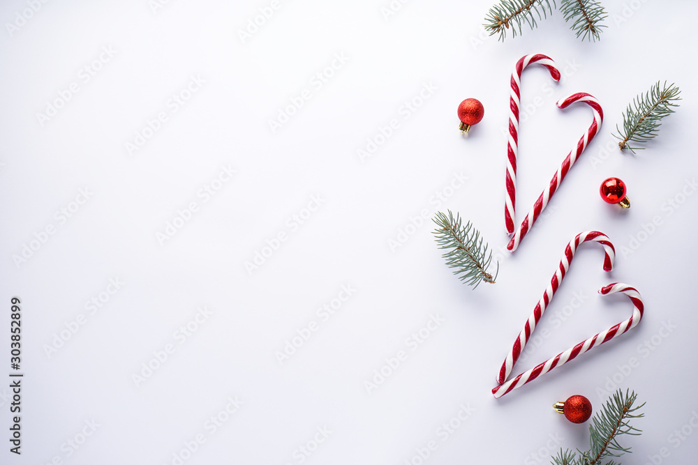 Christmas concept. Christmas candies with red balls and blue spruce branches on a white background. Place for text, flat lay. Christmas concept. Christmas candies with red balls and blue spruce branches on a white background. Place for text, flat lay.