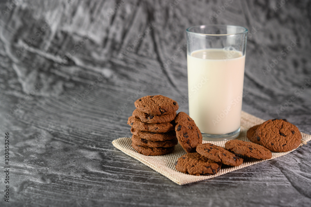 A pile of cookies and a glass of milk on a cloth on a wooden table A pile of cookies and a glass of milk on a cloth on a wooden table