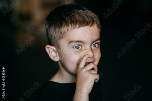 Child little boy picking his nose with his finger.