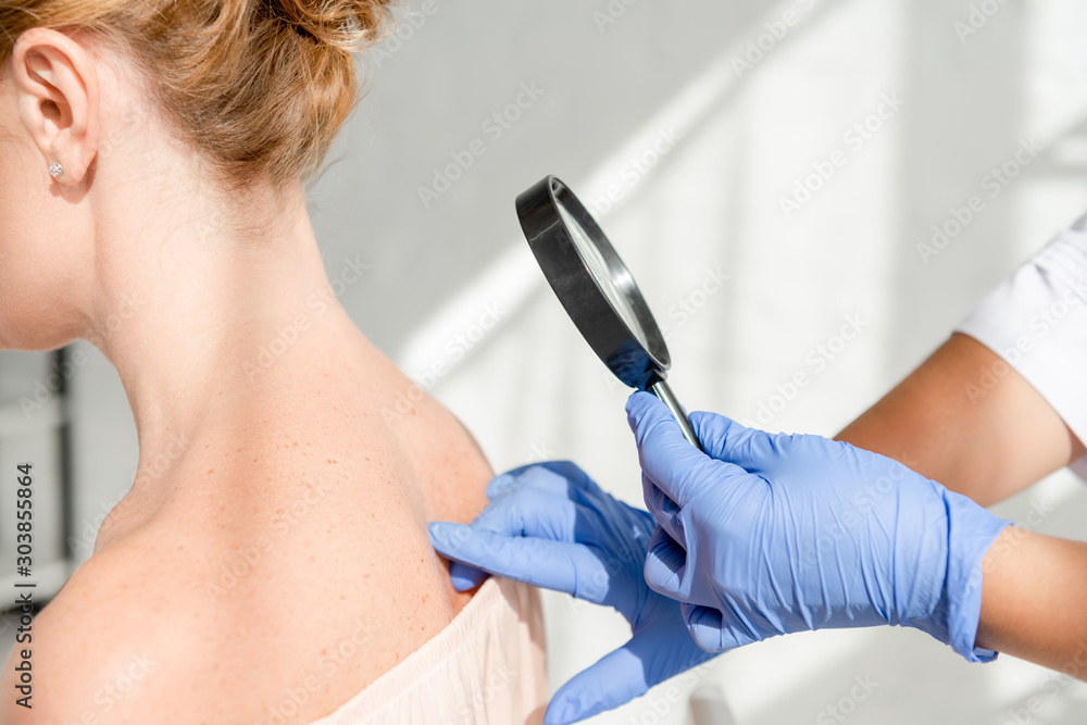 Φωτογραφία cropped view of dermatologist examining skin of patient with magnifying glass in