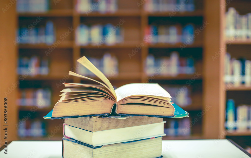 Stack of books in the library and blur bookshelf background Stack of books in the library and blur bookshelf background