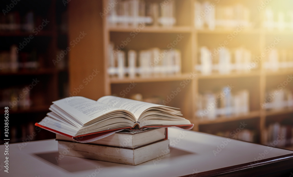 Fototapeta premium Stack of books in the library and blur bookshelf background