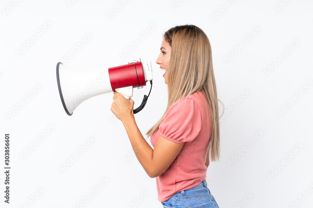 Young blonde woman over isolated white background shouting through a megaphone Young blonde woman over isolated white background shouting through a megaphone