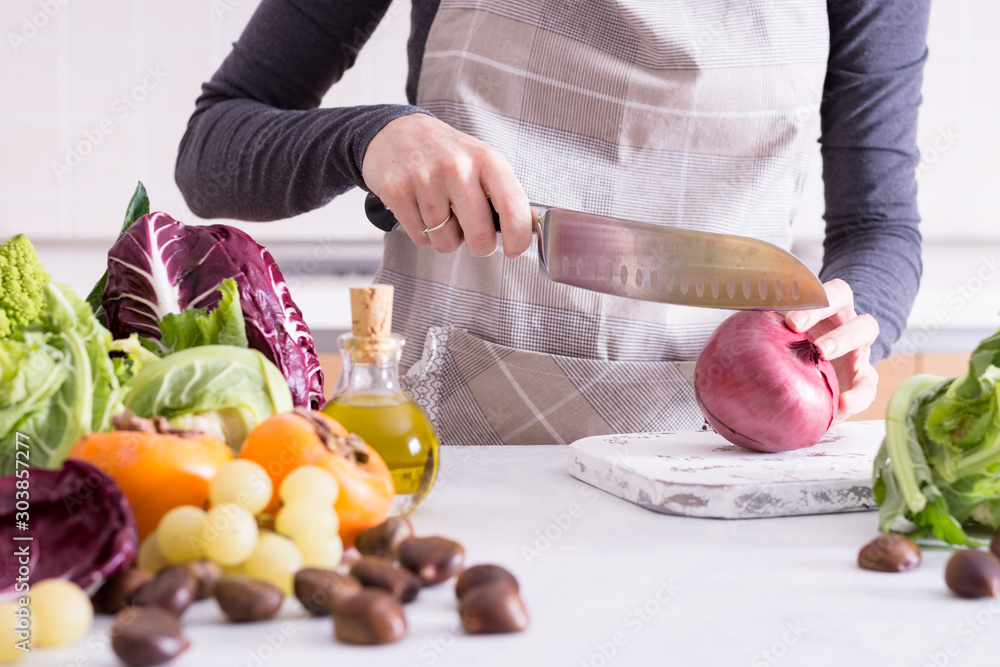 Young woman cooking in the kitchen. Mother is cutting autumn vegetables for the dinner with her family. Cooking seasonal food for a healthy meal. Young woman cooking in the kitchen. Mother is cutting autumn vegetables for the dinner with her family. Cooking seasonal food for a healthy meal.