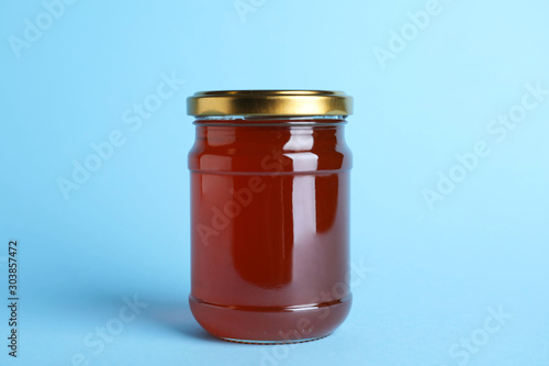 Jar of organic honey on light blue background