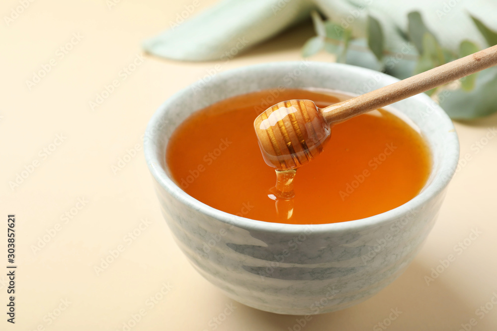 Bowl of organic honey and dipper on beige background Bowl of organic honey and dipper on beige background