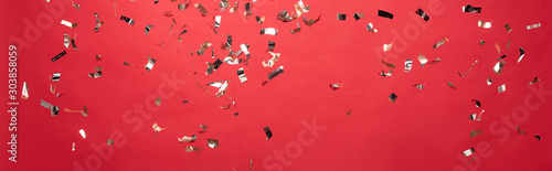 panoramic shot of christmas golden confetti isolated on red