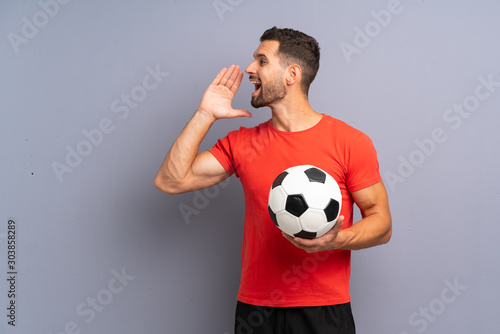 Handsome young football player man over isolated white wall shouting with mouth wide open