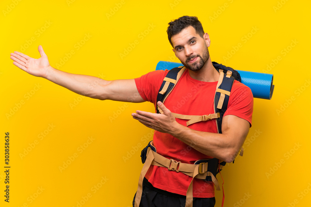 Young hiker man extending hands to the side for inviting to come Young hiker man extending hands to the side for inviting to come