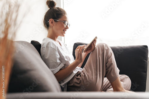 Image of beautiful woman smiling and typing on cellphone photo