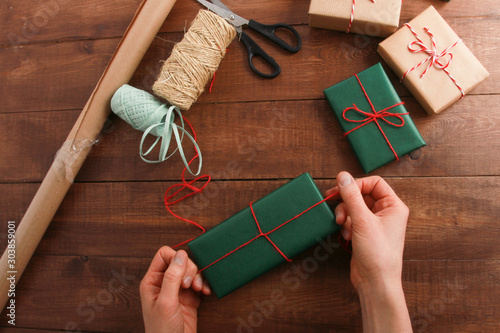 Hands of woman wrapping Christmas and New Year gifts. Present packing concept. Boxes, ribbons, strings, bows, scissors