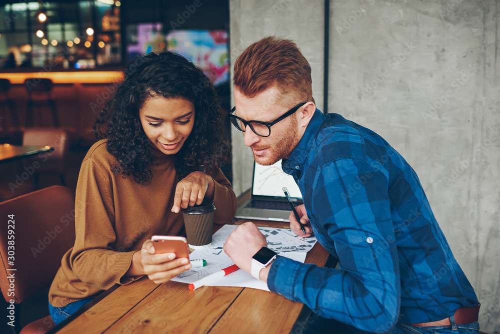 Fotografie Young male and female students looking attentively on video browsed on smartphon