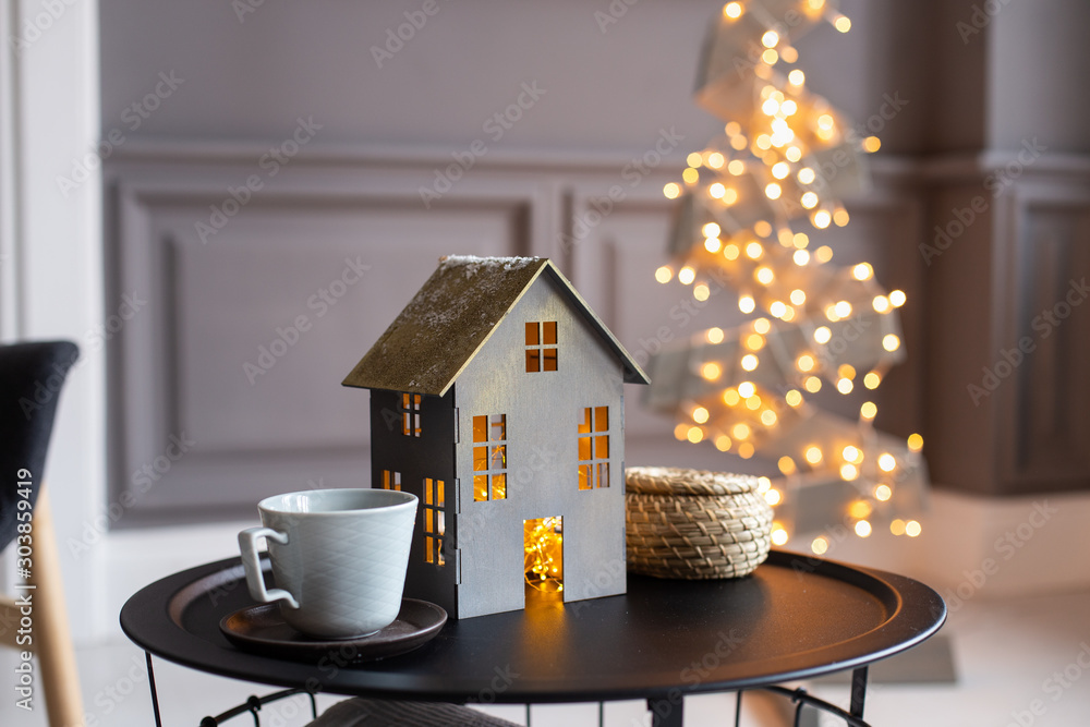 Φωτογραφία Closeup of paper house and two empty cups on a black table and a fir of wooden p
