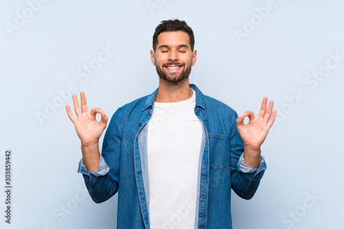 Handsome man over isolated blue background in zen pose