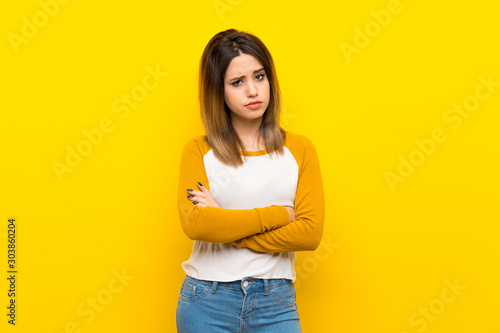 Pretty young woman over isolated yellow wall feeling upset