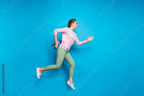Full length profile photo of pretty lady long braids jumping high sports competition run to finish line wear casual pink pullover green pants isolated blue color background