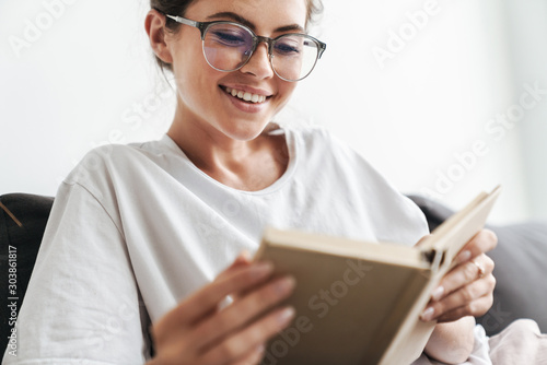 Image closeup of joyful caucasian woman reading book while sitting