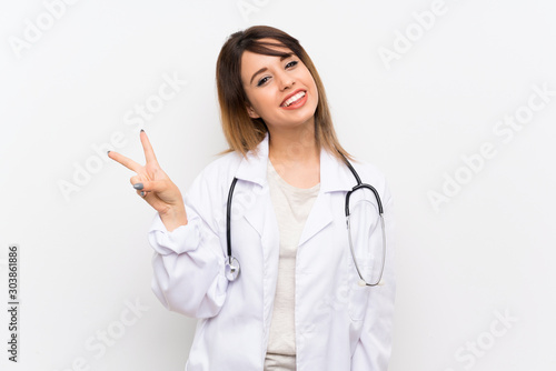 Young doctor woman over isolated background smiling and showing victory sign
