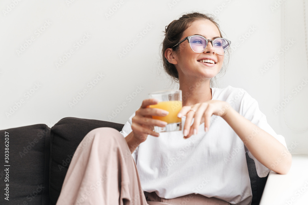 Image of laughing nice woman looking aside and drinking juice Image of laughing nice woman looking aside and drinking juice