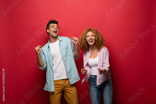 beautiful excited couple in casual clothes isolated on red