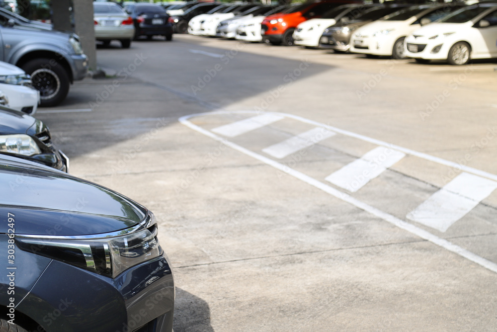 Closeup of front side of blue car with  other cars parking in outdoor  parking lot in bright sunny day.