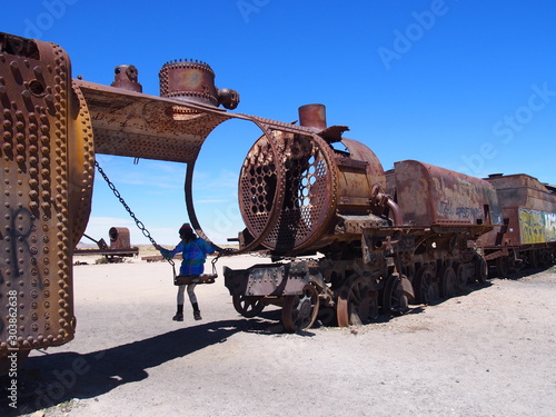 A woman tourist sits on a swing built into a rusty old train at the Train Cemetery (Cementerio de Trenes), Salar de Uyuni, Salar de Uyuni is the world's largest salt flat, Bolivia
