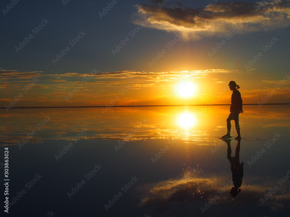 Groom backlit by a beautiful sunset, the groom is standing on a salt lake with the landscape reflected, Salar de Uyuni, Salar de Uyuni is the world's largest salt flat, Bolivia