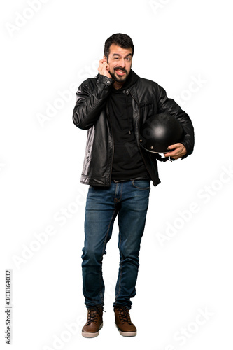 Full-length shot of Biker man frustrated and covering ears over isolated white background