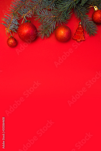 Evergreen branch with red Christmas ball on red background. New Year banner with place for text