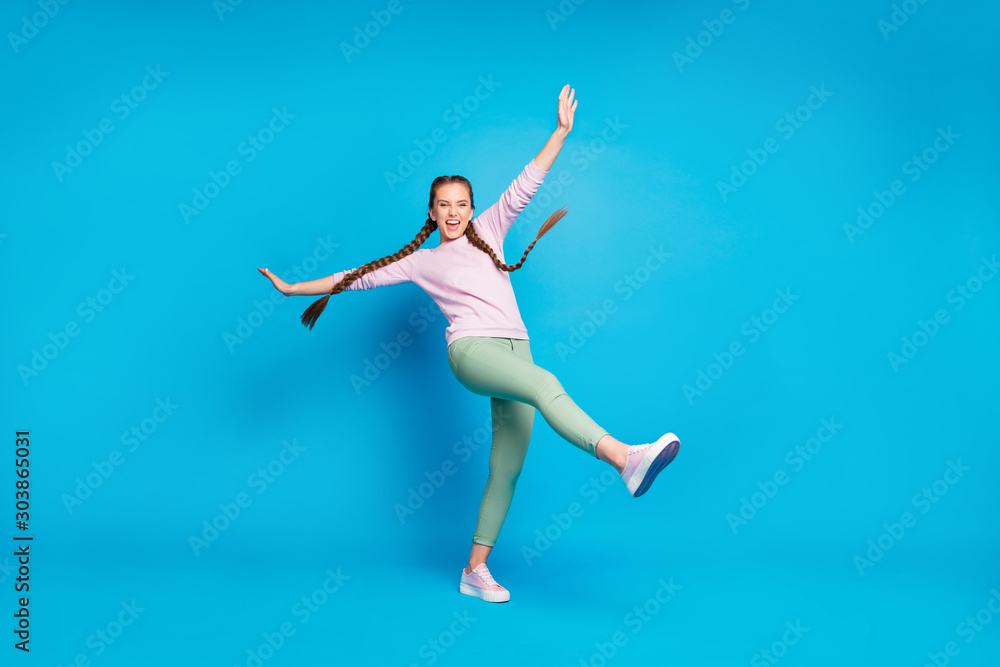 Full size photo of cute millennial girl have fun on spring holidays raise hands legs shout feel funny wear casual modern outfit isolated over bright color background