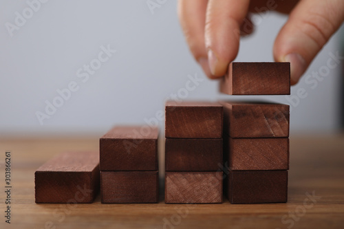 Fotografie Male hand holds brown wood block of stair finish