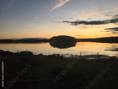 Sunset over the forest and islands of an inlet on the Atlantic Ocean along the Maine Coast. Bright colors reflecting off a tranquil water with clouds rolling overhead