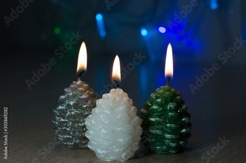 Christmas candles on a blurred background of garland lights.