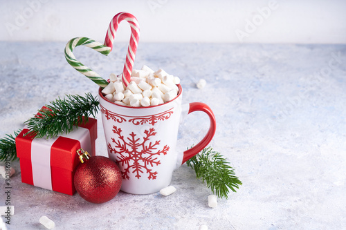 Christmas cup with sugar cocoa marshmallows and candy . Fir branches, christmas gift box on light background Copy space.