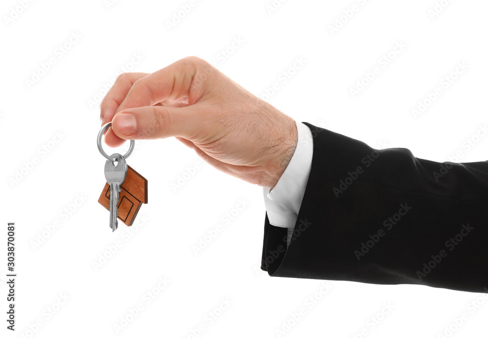 Real estate agent holding house key with trinket on white background, closeup Real estate agent holding house key with trinket on white background, closeup