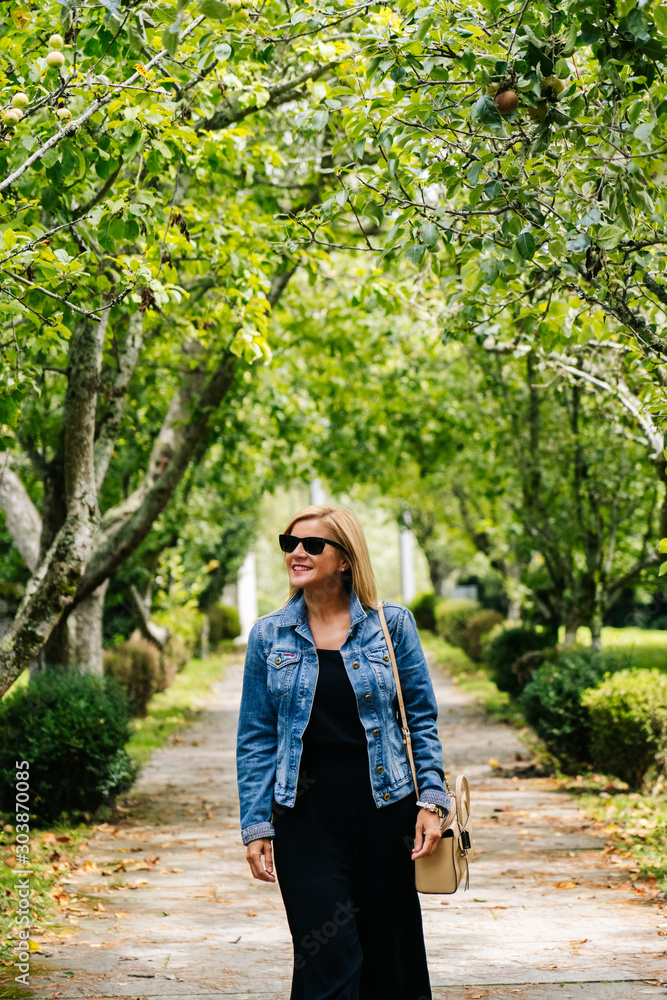 A beautiful caucasian blonde woman walks through a park A beautiful caucasian blonde woman walks through a park